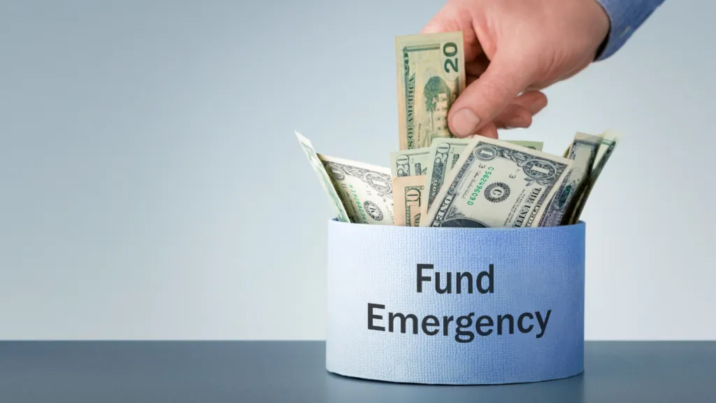 a jar written "emergency funds" with several notes inside and someone inserting more notes