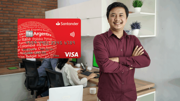 Hombre sonriente en una oficina moderna, con una tarjeta de crédito internacional Santander Visa destacada al frente.