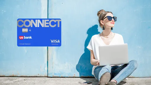 woman using a computer while reviewing her U.S. Bank Altitude Connect Visa Signature credit card