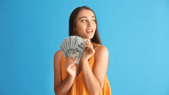 Mujer sosteniendo dólares estadounidenses, ilustrando el uso del dólar blue como una alternativa a la cotización oficial.