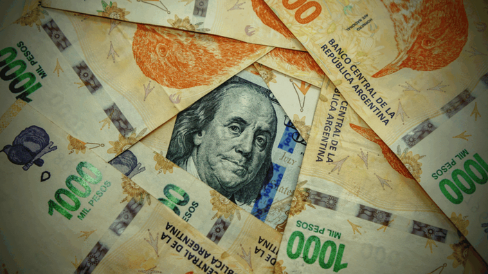 Billetes de pesos argentinos junto a un billete de dólar estadounidense, ilustrando conceptos de inversiones seguras en Argentina como el dólar blue y otras opciones de inversión.