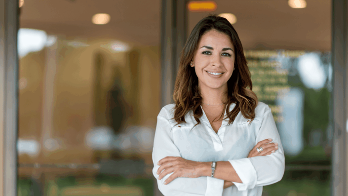Mujer sonriente en un entorno profesional, reflejando seguridad y confianza, elementos esenciales al considerar inversiones seguras en Argentina para proteger el patrimonio personal.