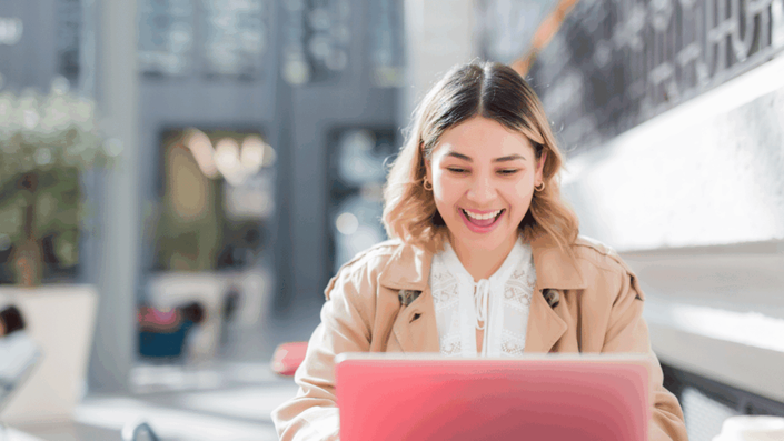 Joven sonriendo mientras revisa información del Monotributo en Argentina en su laptop, en un ambiente moderno y luminoso.