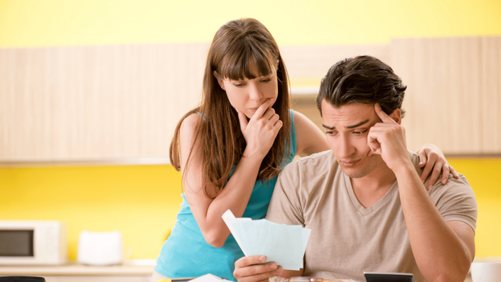 Pareja preocupada revisando sus finanzas y presupuestos personales en su hogar, trabajando en la creación de un presupuesto personal efectivo para manejar sus gastos e ingresos.